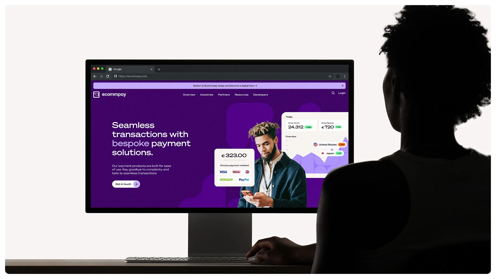 Person looking at a computer screen displaying a financial technology website, featuring a man, data charts, and payment options.