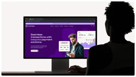 Silhouette of a person viewing a computer monitor displaying a purple website for Ecommpay with UI elements.