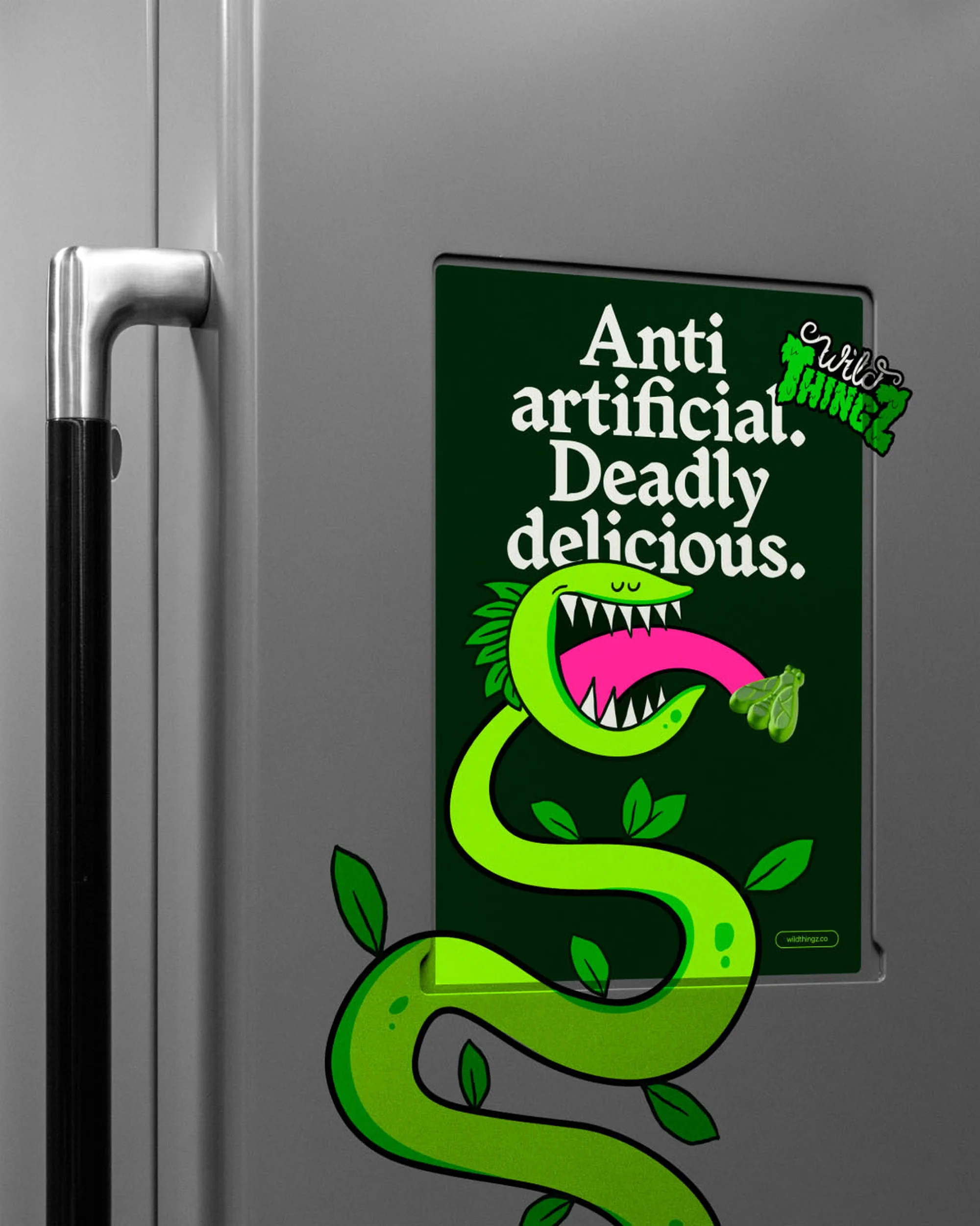Illustration of a green cartoon snake on a refrigerator door, with an advertisement reading 'Anti artificial. Deadly delicious.'
