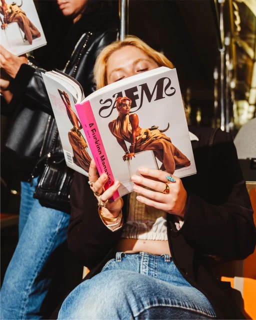 Two women seated indoors reading copies of 'AFM' magazine, with focus on the blonde woman holding the magazine open.