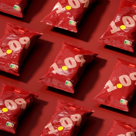 Overhead shot of multiple red bags of chips, featuring a yellow price tag, arranged in a repeating pattern on a red background.