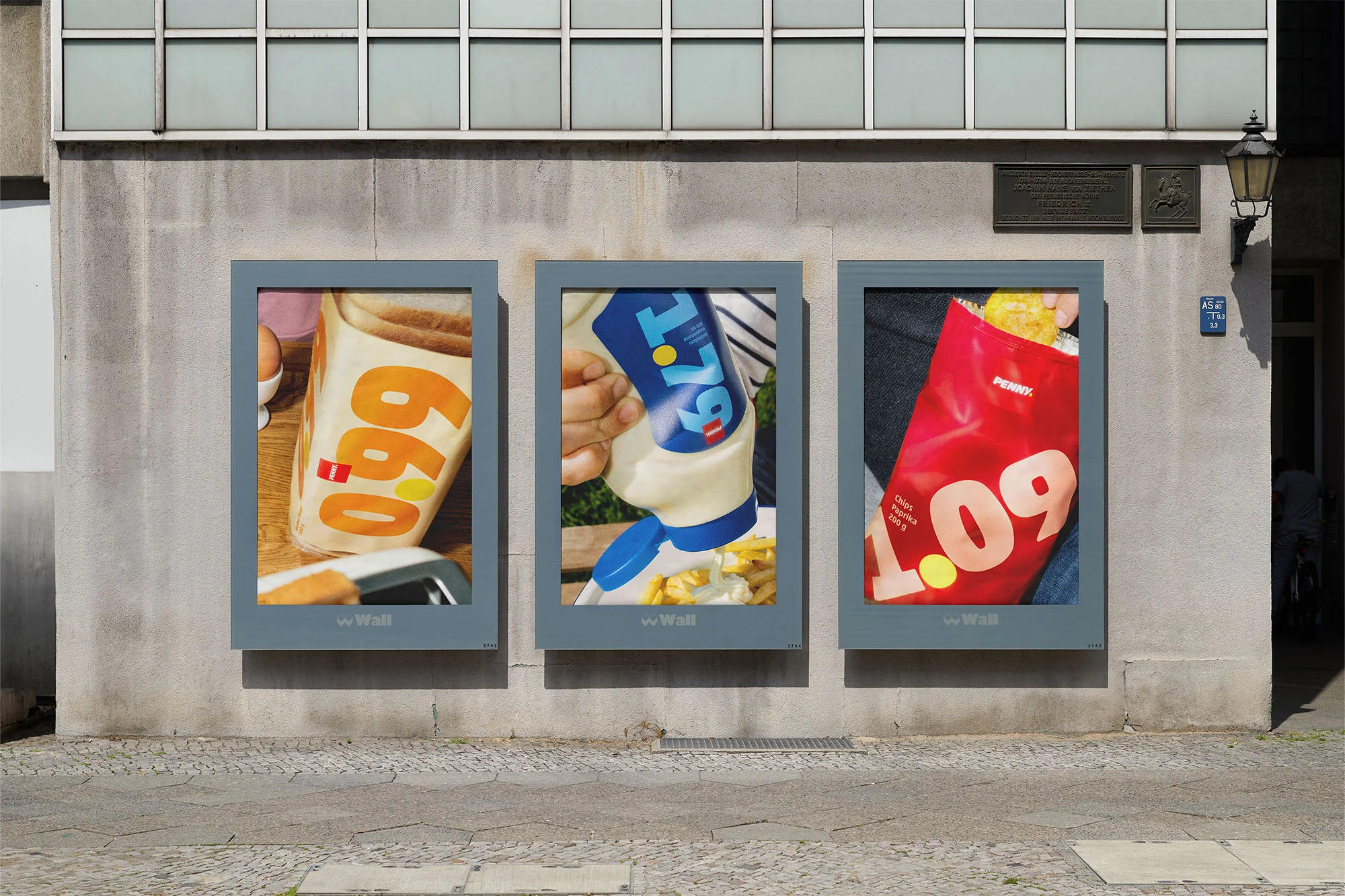 Three framed food advertisements on a textured exterior wall feature toast, mayonnaise, and fried food with bright graphic text.