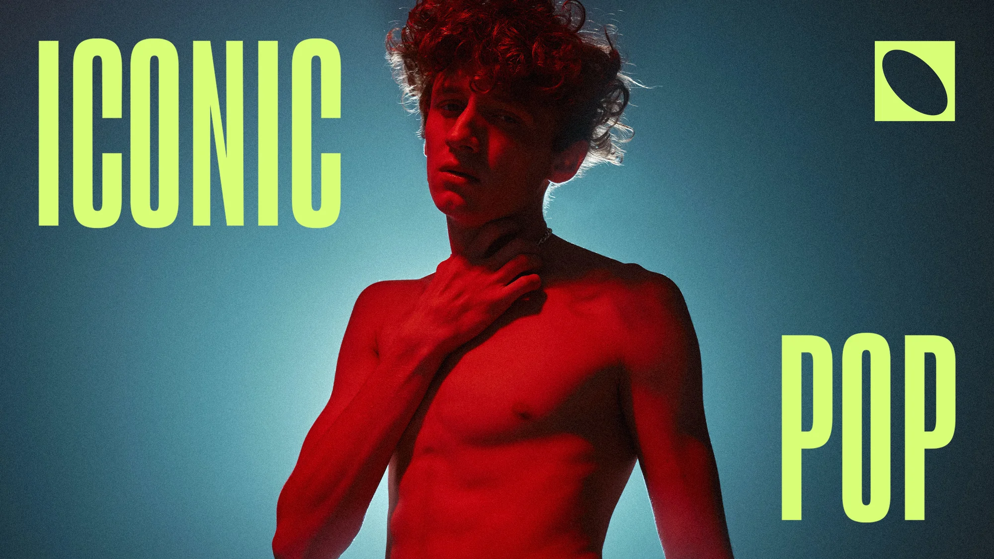 Close-up of a bare-chested young adult male with curly red hair, illuminated by red lighting, against a soft blue backdrop with text.