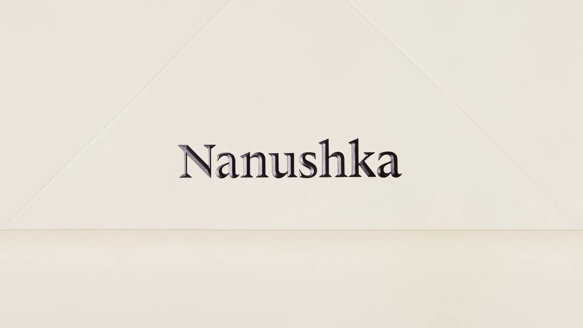 Studio shot of a Nanushka package, displaying the brand logo and a geometric design on a neutral background.