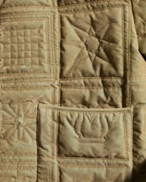 Close-up detail of tan quilted fabric with stitched geometric and star patterns