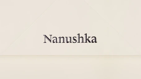 Embossed Nanushka brand typography centred on a minimal cream paper background