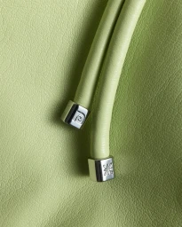 Macro view of light green leather texture with parallel cylindrical cords featuring silver metal end caps.
