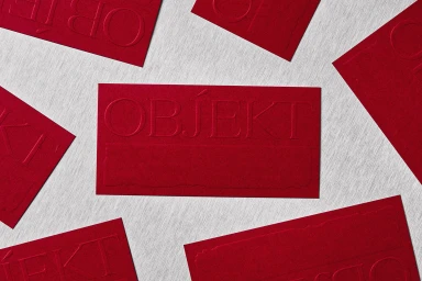 Red embossed print cards featuring the OBJEKT brand name arranged across a light grey textured background