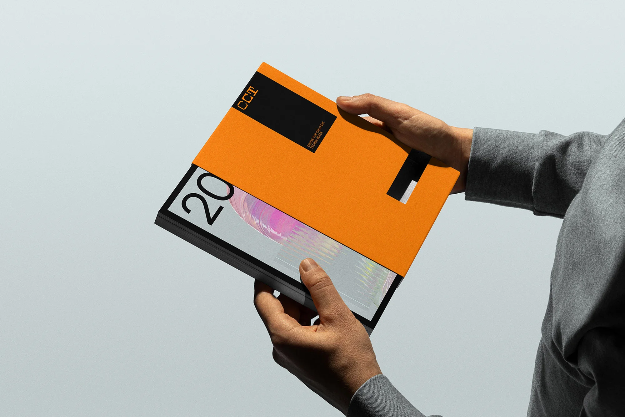 A person holds an open, orange book with black and white text on a light background, showing its holographic interior pages.