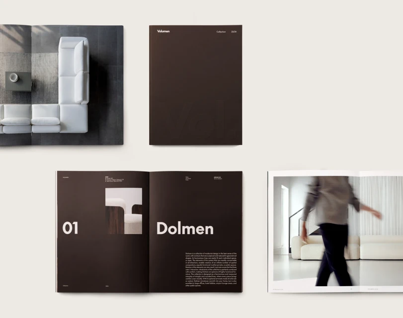 Catalog featuring interior design with a white sectional sofa, hardcover book, and open book with furniture and blurred human. 