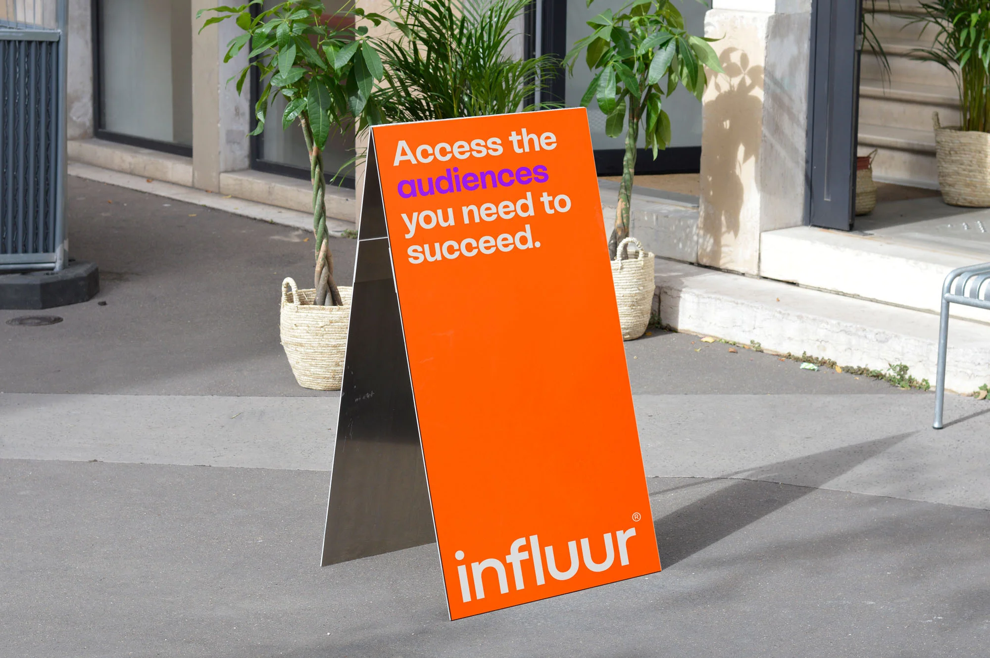 An outdoor A-frame sign displays 'Access the audiences you need to succeed' with the 'influur' logo, promoting a company or service.