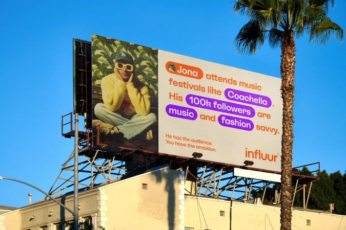 Billboard featuring a person in a yellow sweater and cap, with text about music festivals and followers, alongside a palm tree and building.