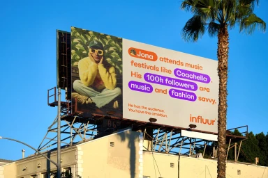 Influur brand identity outdoor billboard featuring graphic typography and a person wearing yellow sunglasses against a blue sky.