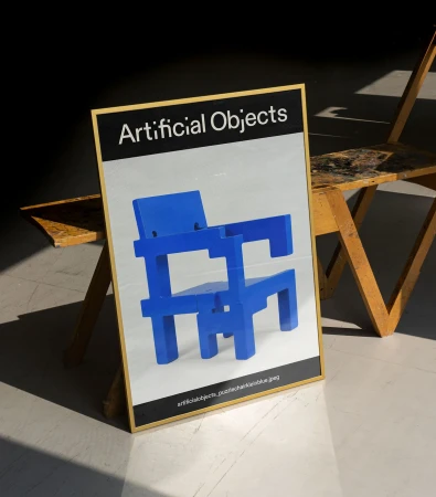 Poster art of a blue geometric chair, displayed indoors against a dark background, adjacent to a light wood-frame easel.