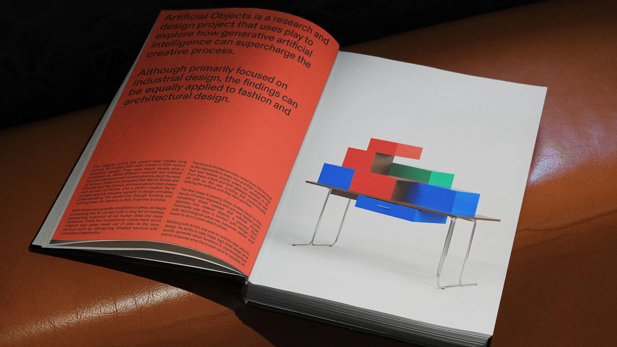 Open book with red and white pages, displaying colorful block-shaped table design, set on a brown surface in indoor environment.