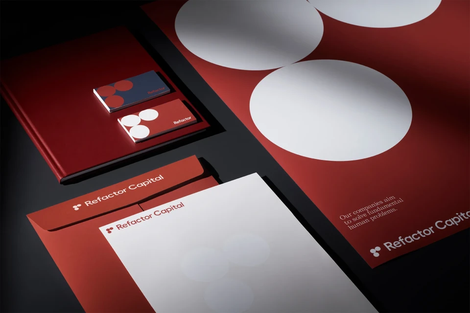 Corporate identity set featuring a red folder, business cards, envelope, and white paper with the Refactor Capital logo on a dark surface.