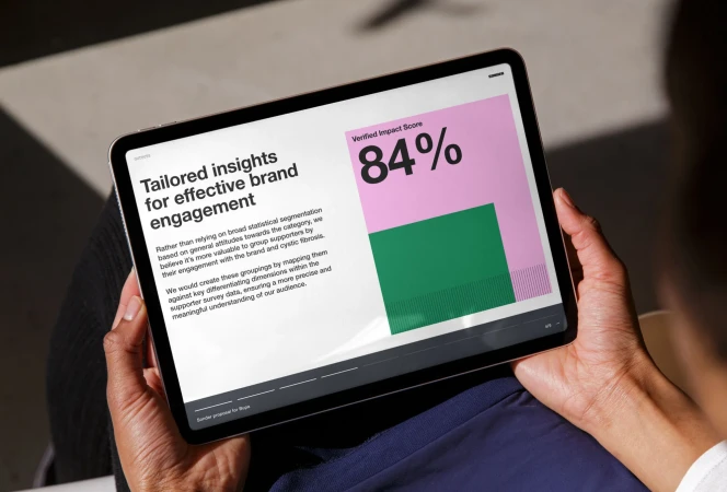 Person holding an iPad displaying data insights, showing text about effective brand engagement and a verified impact score of 84%.