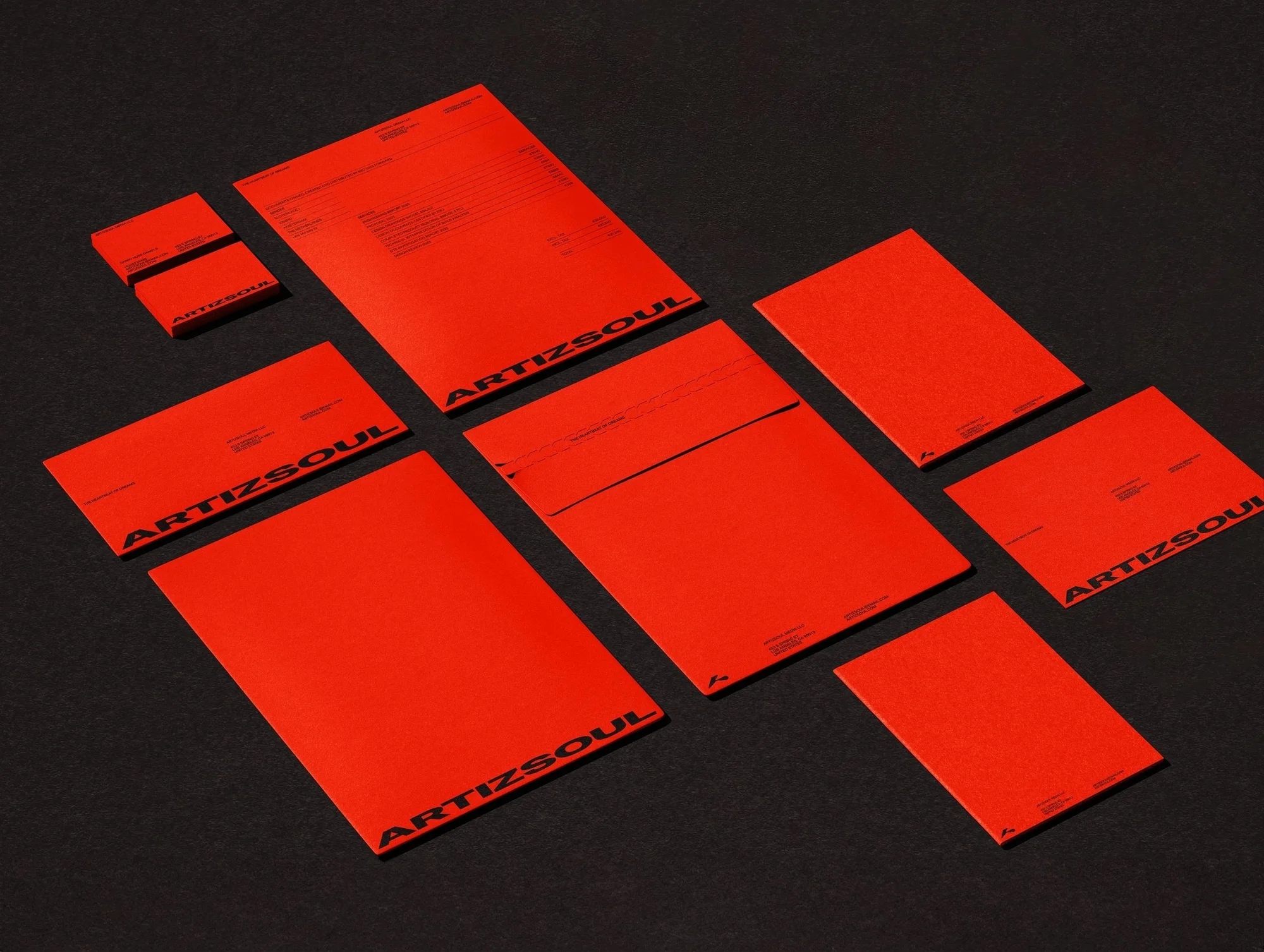 Arrangement of red stationery items with black 'ARTIZSOUL' branding on a dark grey background, creating a striking minimalist presentation.