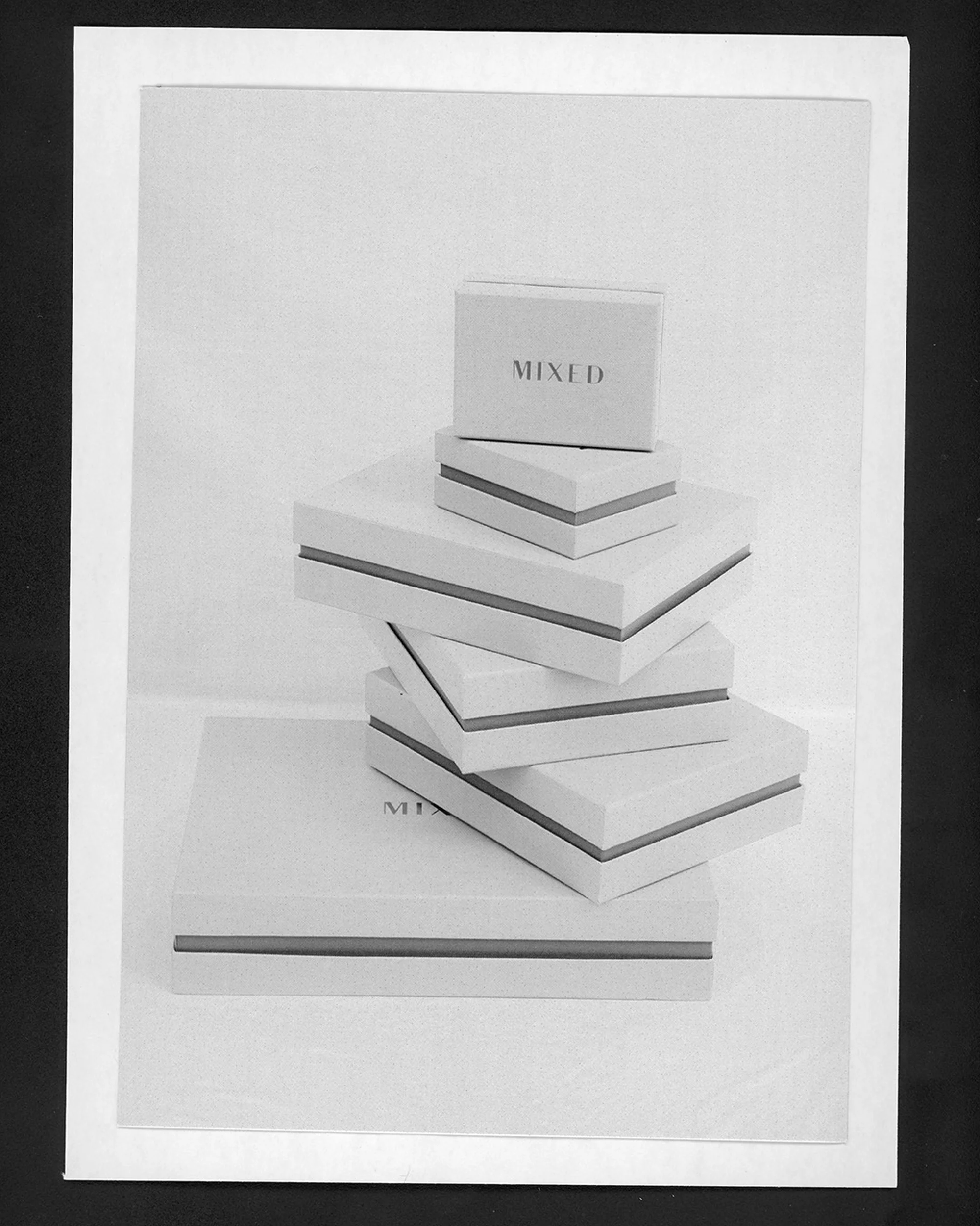 Stacked white boxes with a single stripe around the edge, stacked in front of a solid white background on a white surface.
