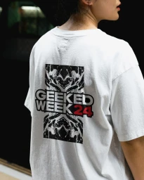 Person wearing a white t-shirt featuring a black graphic print and the text GEEKED WEEK 24 on the back