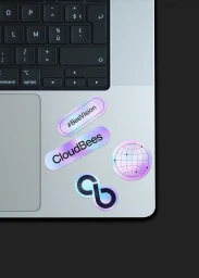 Close-up of a silver laptop keyboard and palm rest decorated with several holographic branded stickers.