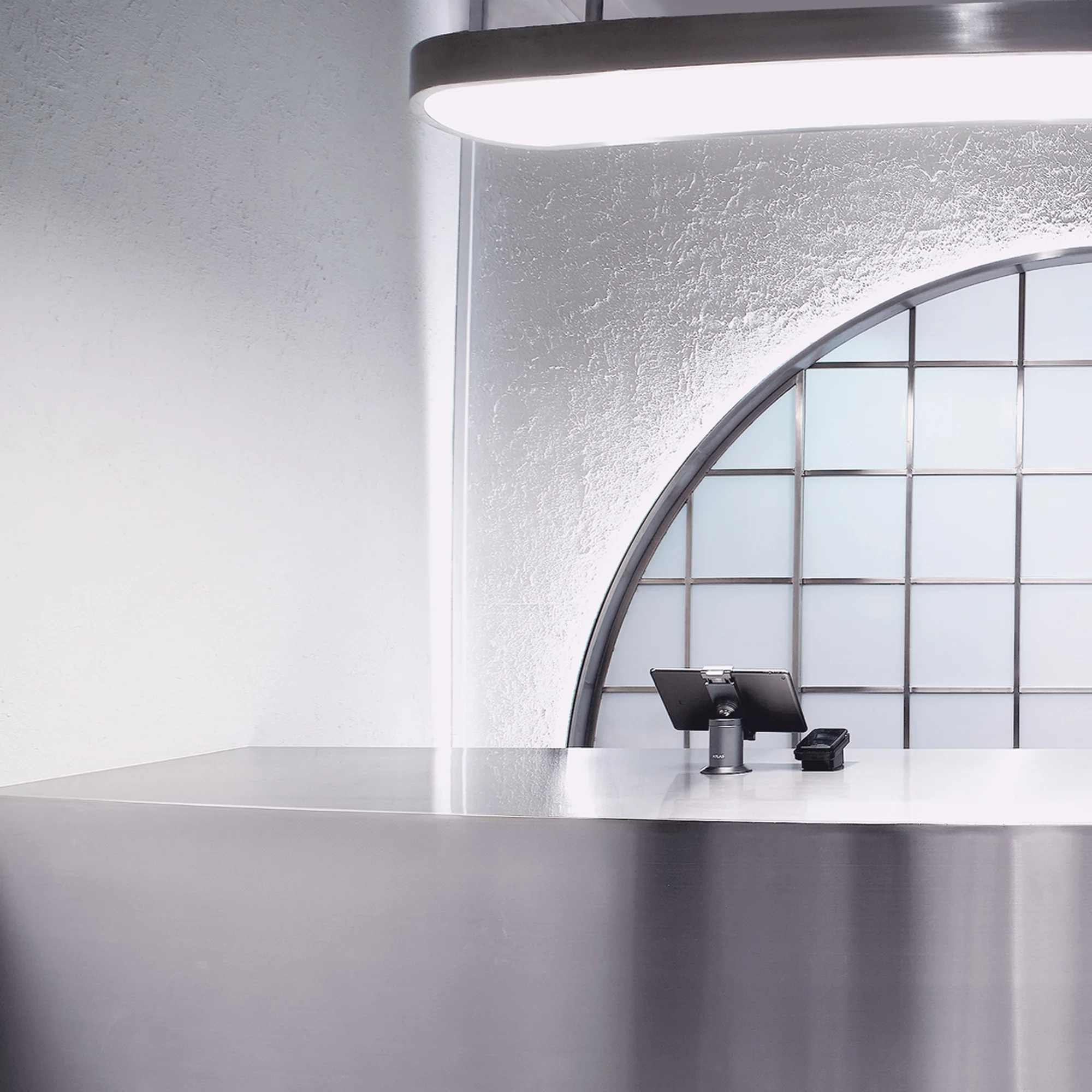 Modern interior featuring a sleek point of sale counter, illuminated by an oval light fixture and an arched window with frosted glass.