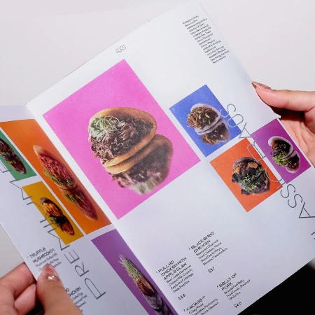 Food menu open with vibrant food images on colorful backgrounds, displaying dishes like pulled chicken, truffle mushroom, and pork belly.