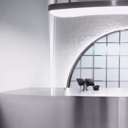 Sleek metallic service counter with tablet POS terminal under a curved modern light fixture and arched grid window.