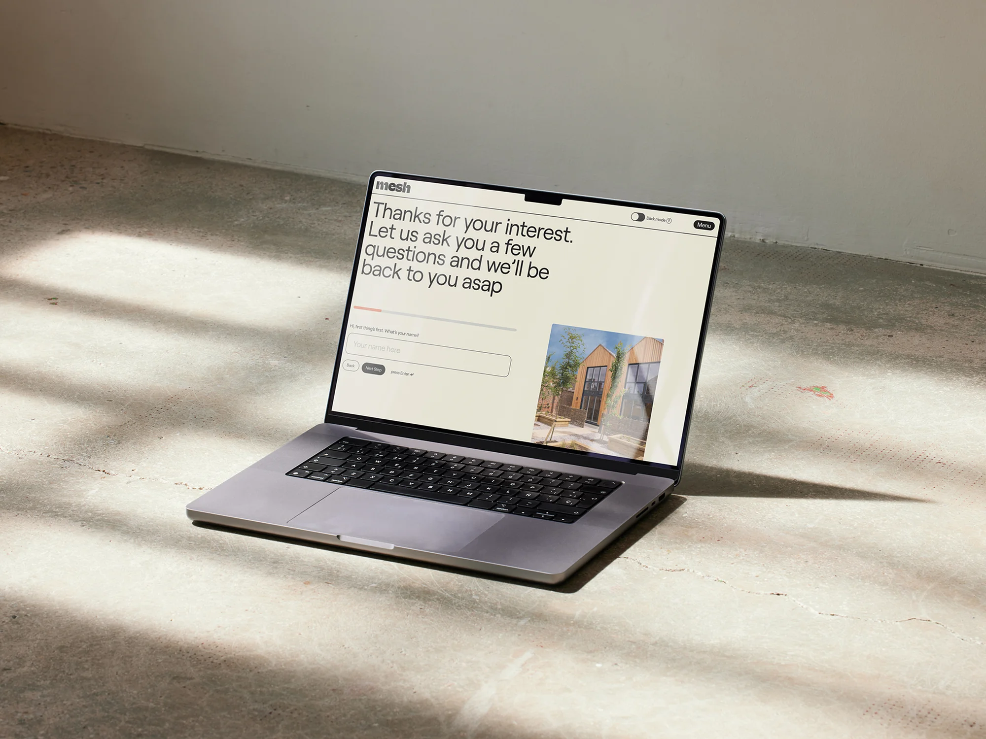 Laptop displaying a minimalist web form with a neutral background, positioned on a concrete surface under bright, diffused lighting.