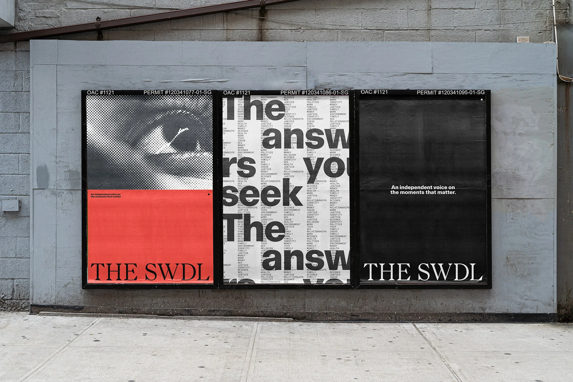Three black-framed poster designs on a gray brick wall feature text and an eye graphic; street-level advertising display.