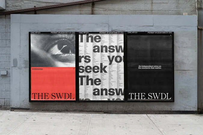 Three black-framed poster designs on a gray brick wall feature text and an eye graphic; street-level advertising display.