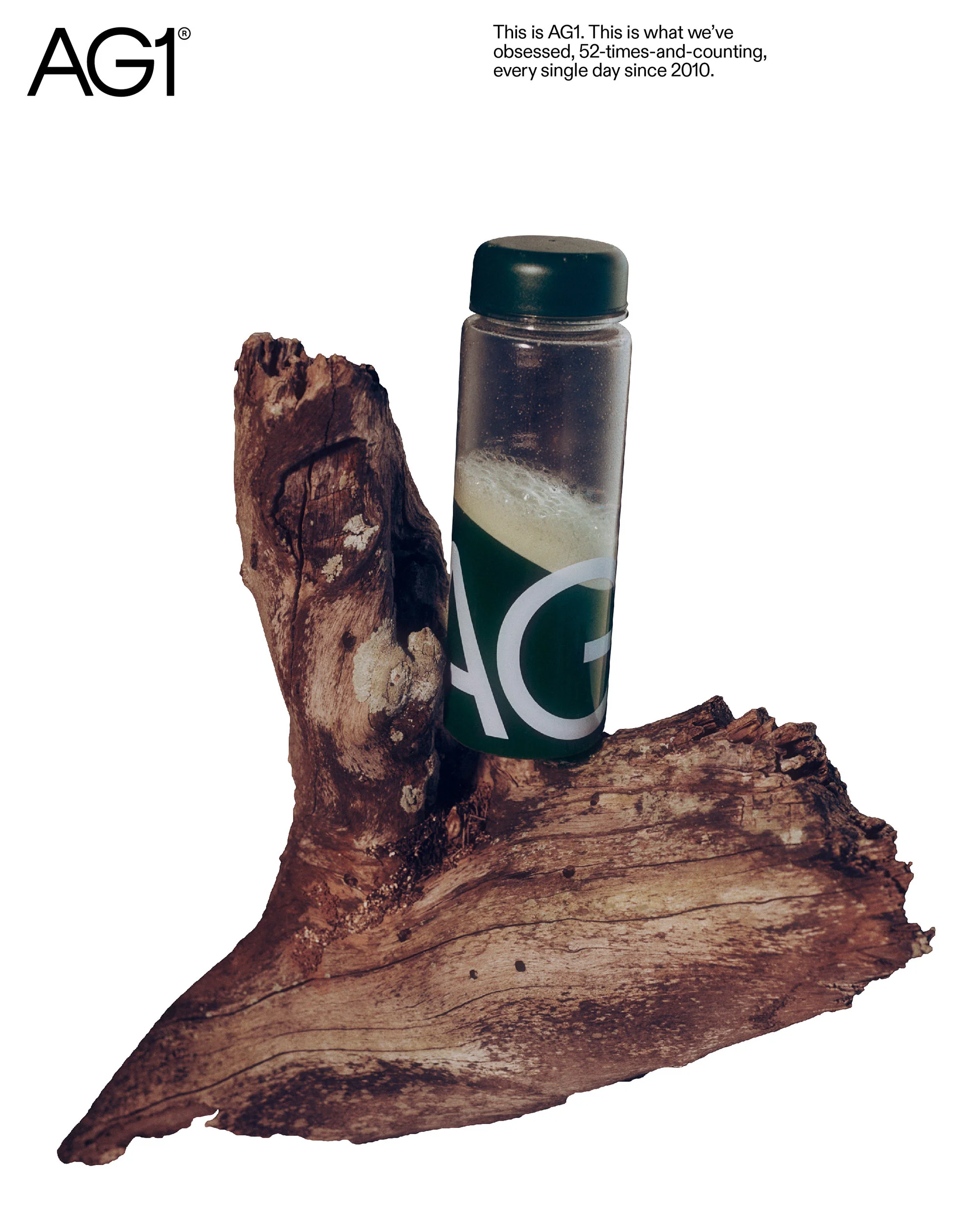 Promotional image for AG1 featuring a bottle of the green health supplement on a textured piece of wood against a white background.