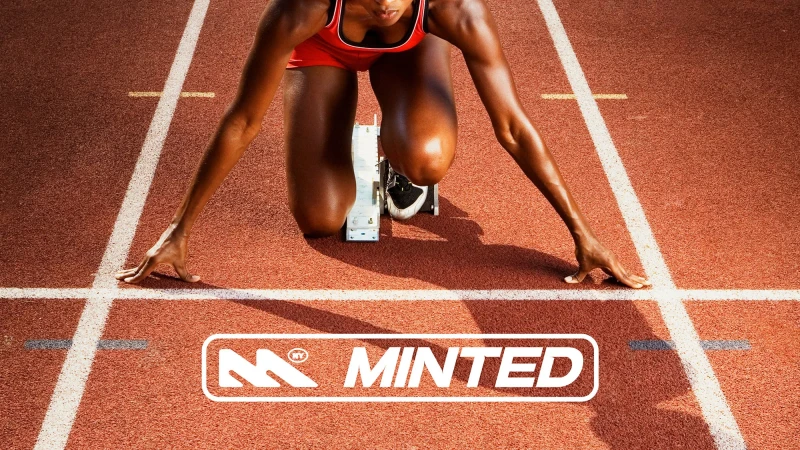 Focused African-American female athlete in starting block on red running track with white lane lines, logo at the bottom of the frame.