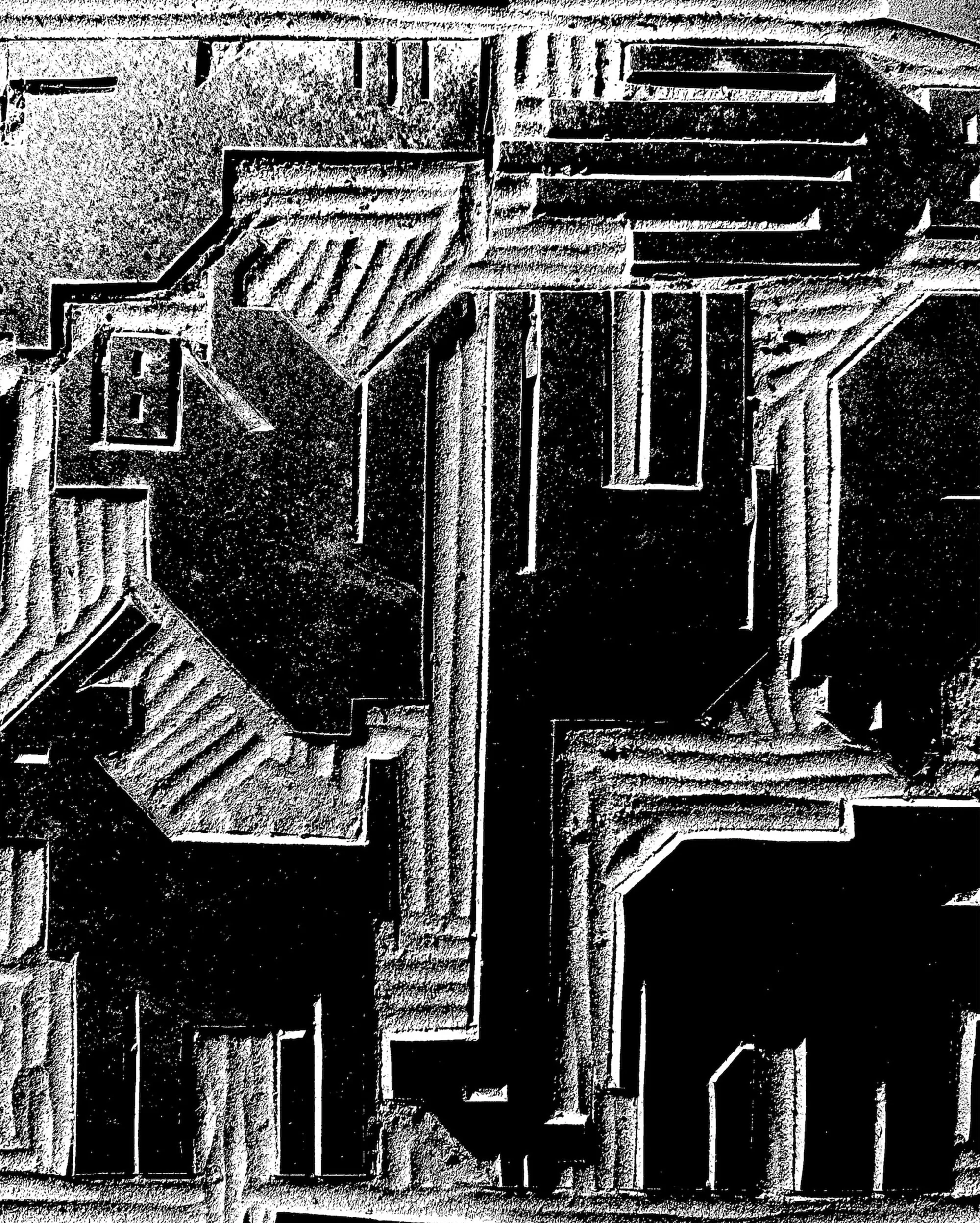 Abstract architectural carving in shades of black and white, featuring geometric shapes and textured surfaces with distinct lines and shadows.