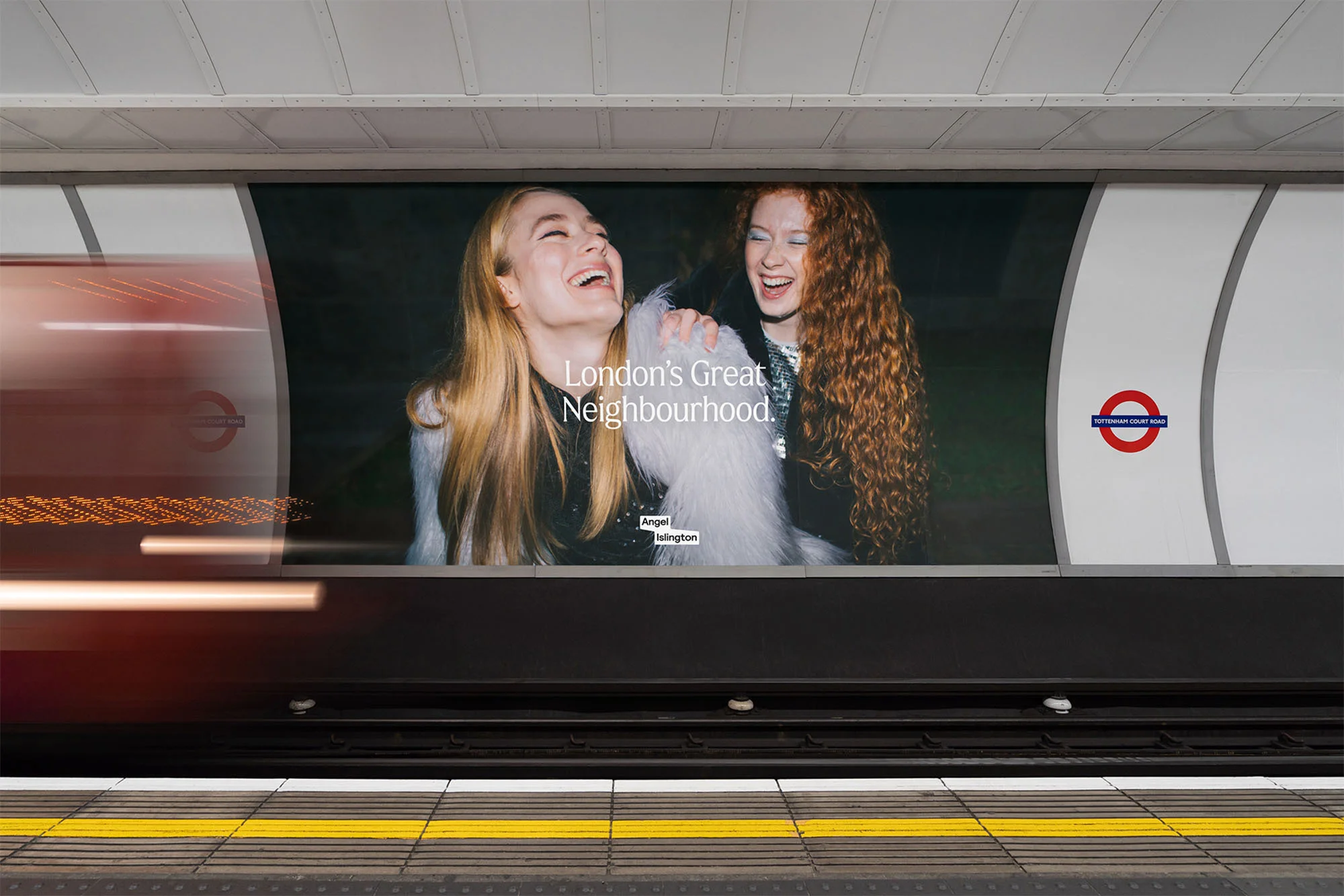 Advertisement in the London Underground featuring two laughing women, promoting Angel Islington as a great neighborhood in London.