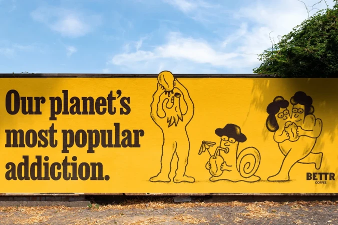 Yellow wall art featuring an illustration of people and a snail with a cocktail, advertising Bettr Coffee against a blue sky background.