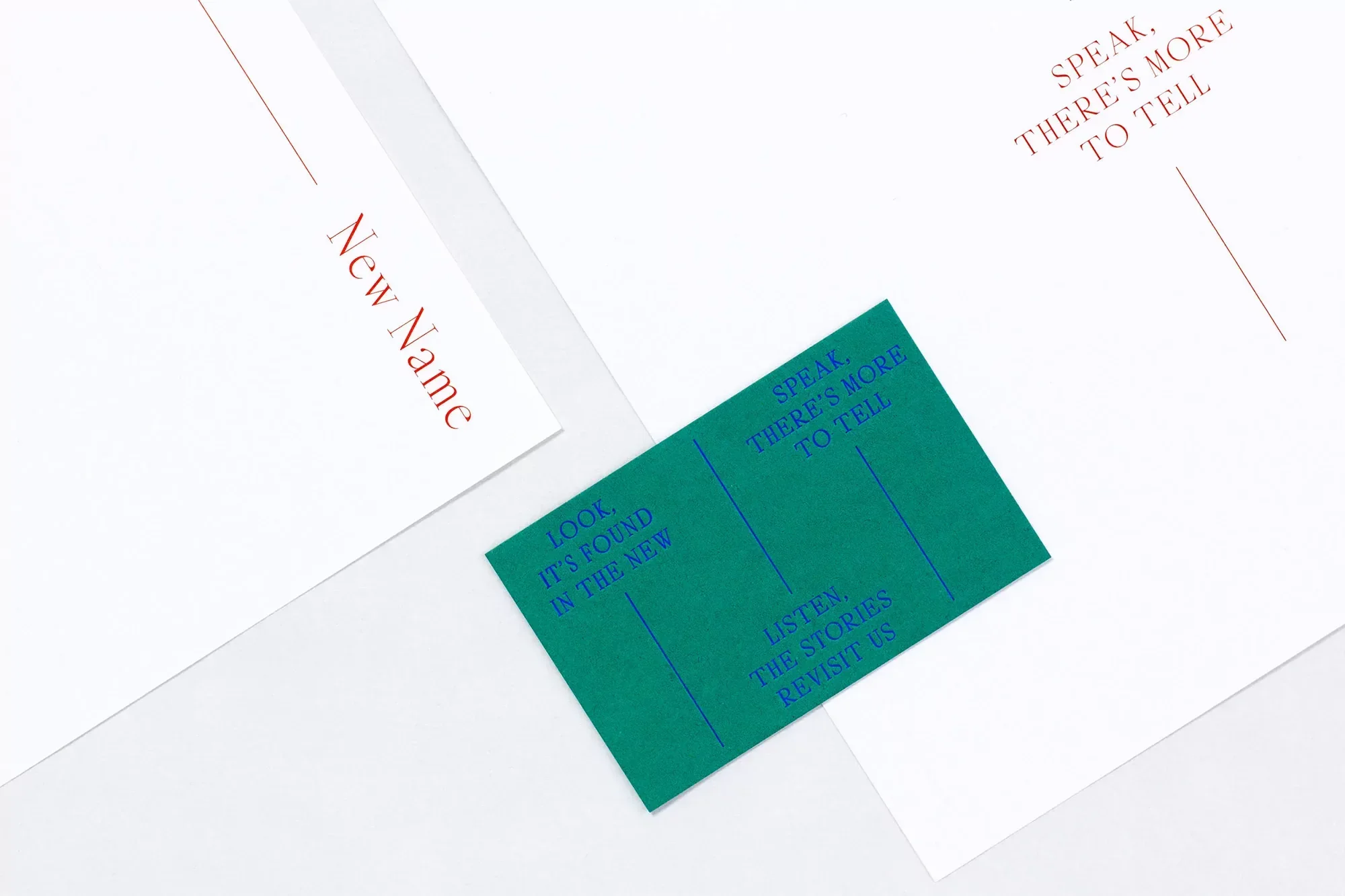 Overhead shot of graphic design elements: white papers with red text, a small green card with blue text, and soft, diffused lighting.