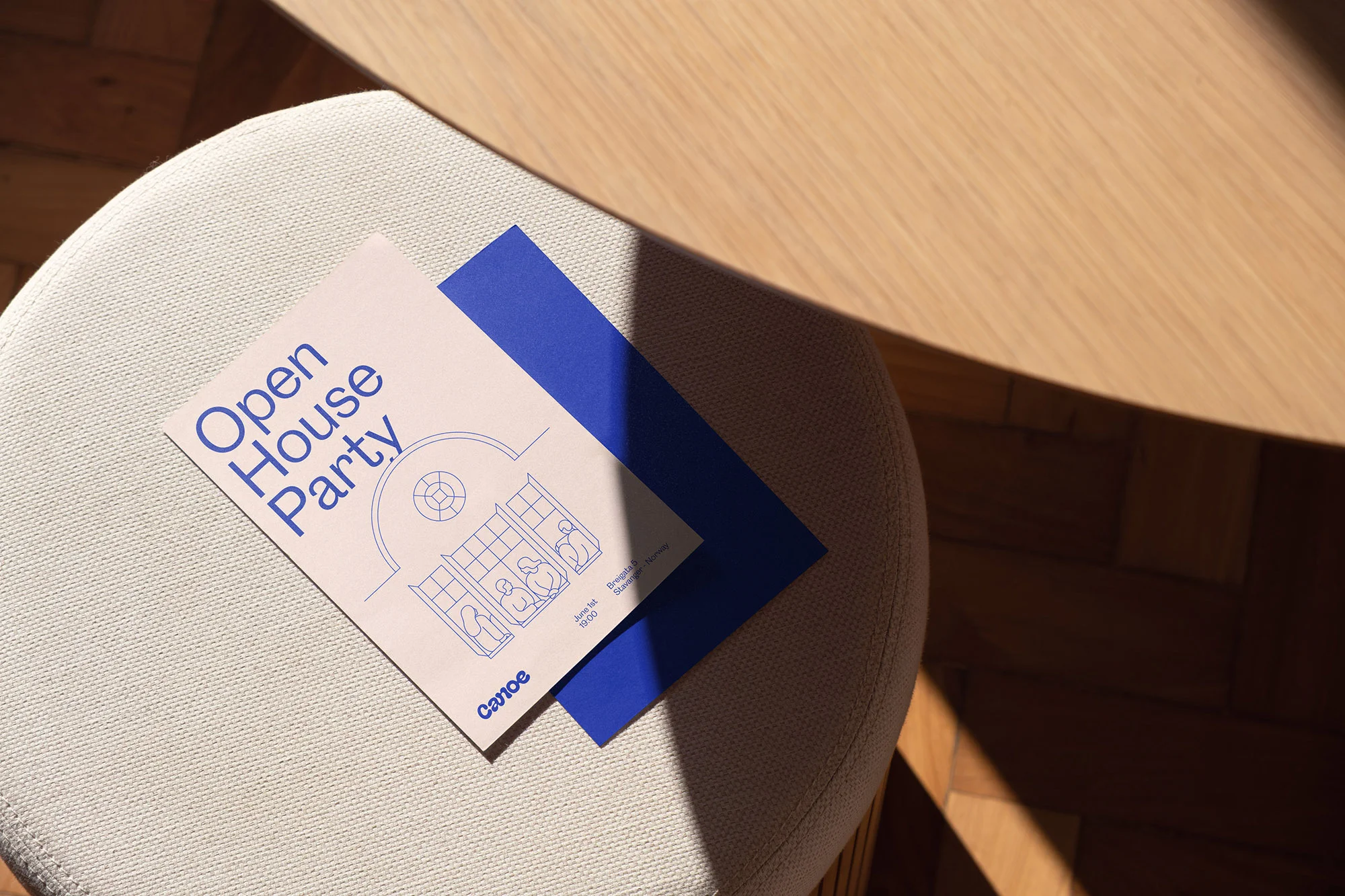 Invitation card for an Open House Party on a textured stool near a light wood table with shadows and geometric minimalist illustration.