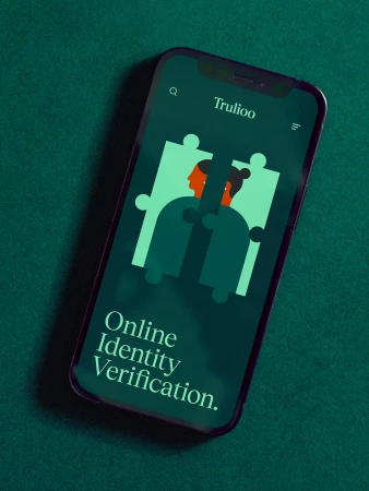 Close-up of a smartphone displaying Trulioo online identity verification app with a puzzle design, set against a green backdrop.