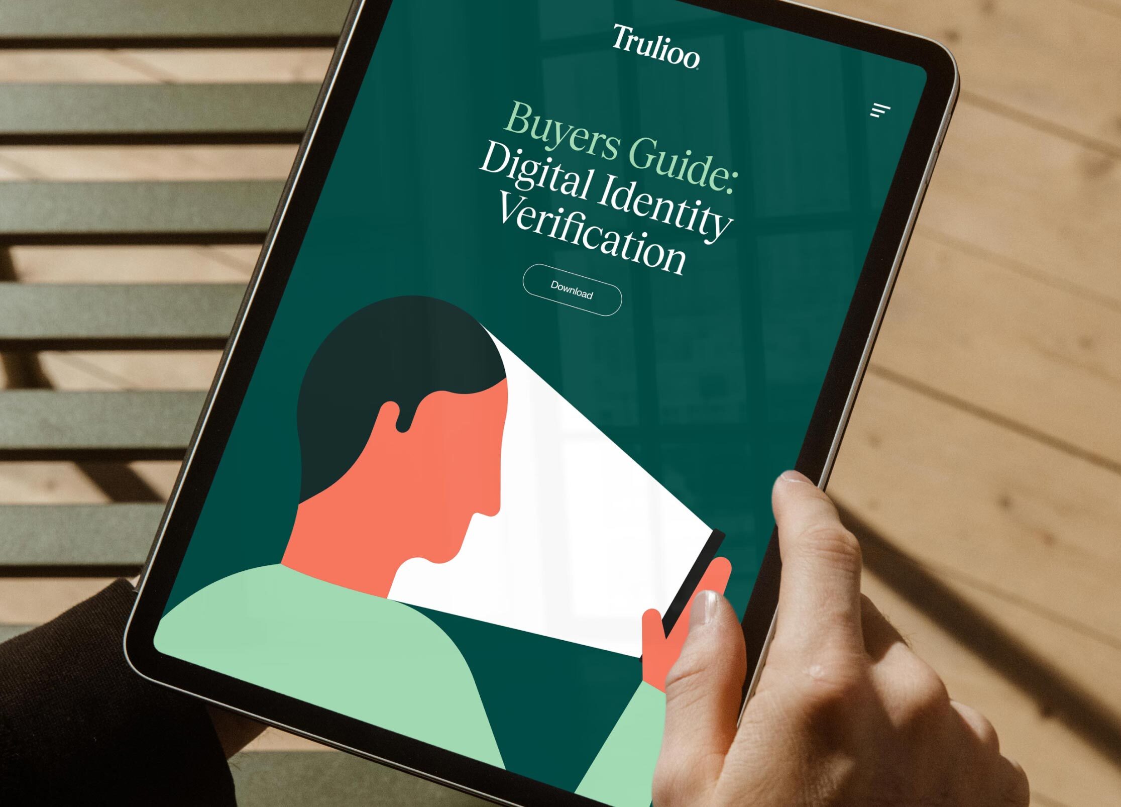 Person holding a tablet displaying a teal-colored digital identity verification guide with an abstract profile of a person.