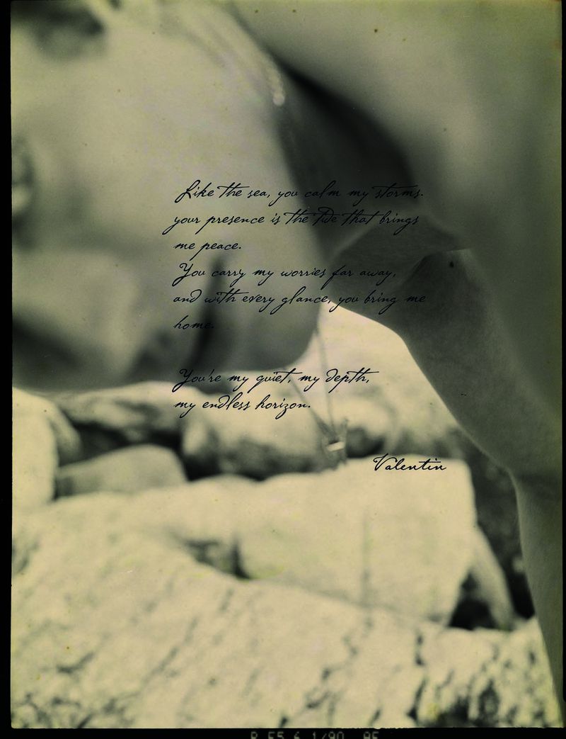 Close-up, black-and-white vintage photo of a woman next to cursive text with ocean themes; rocks visible in the blurred background.