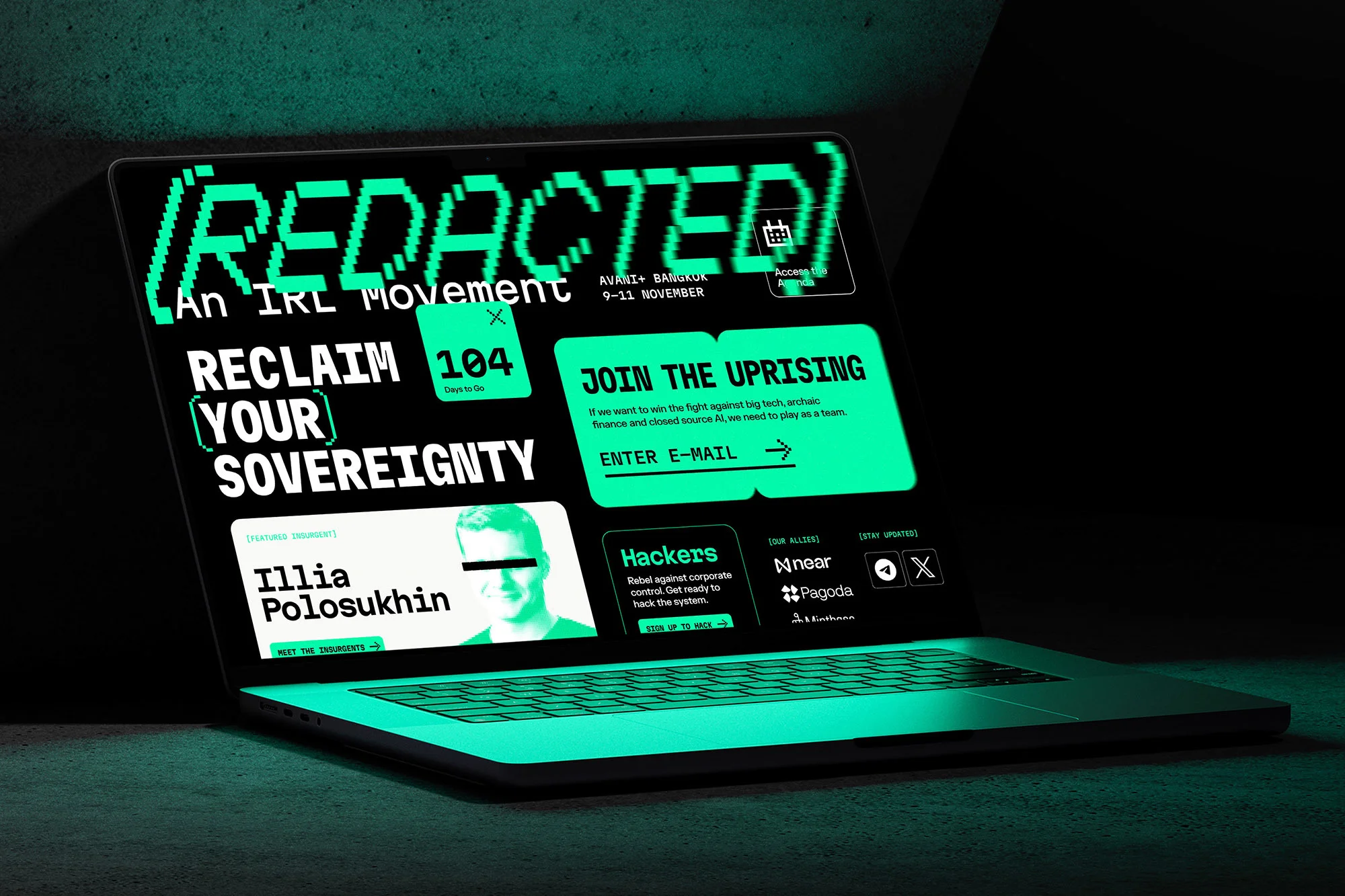 Laptop displaying 'REDACTED: An IRL Movement,' featuring digital event info, portraits, and registration prompts, all in green on black.