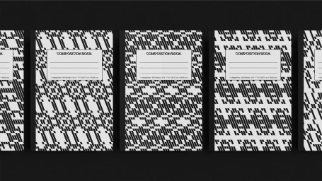 Multiple composition notebooks with black and white patterned covers arranged in a row on a black surface