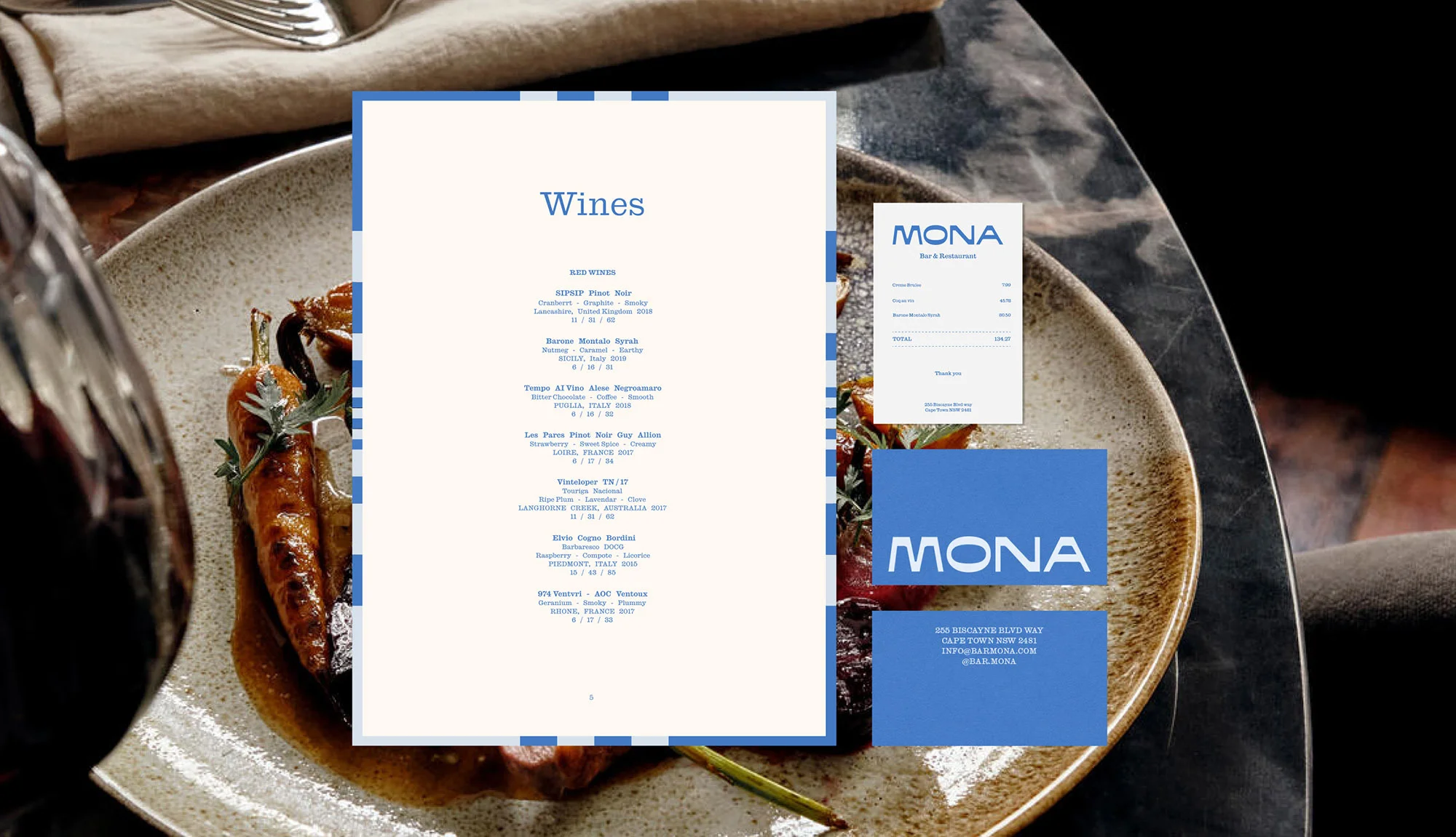 Close-up of a plate with roasted carrots and a glass of red wine, alongside menus and promotional material for Mona Bar & Restaurant.