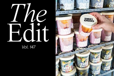 Hand reaching into a store freezer shelf filled with Sweet Cheeks ice cream tubs next to large typography on a black background
