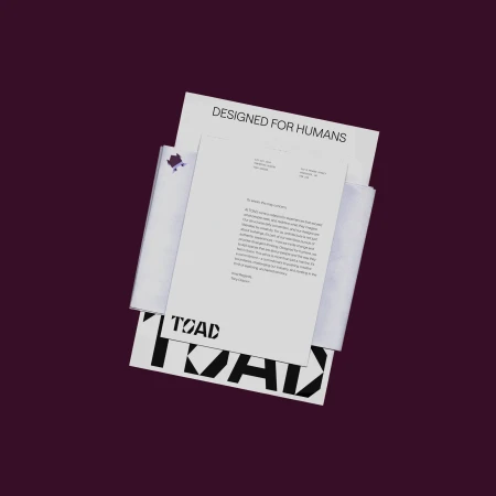 Close-up of letterhead, stationery, and branding for Toad, featuring design and text elements on white paper against a dark background.