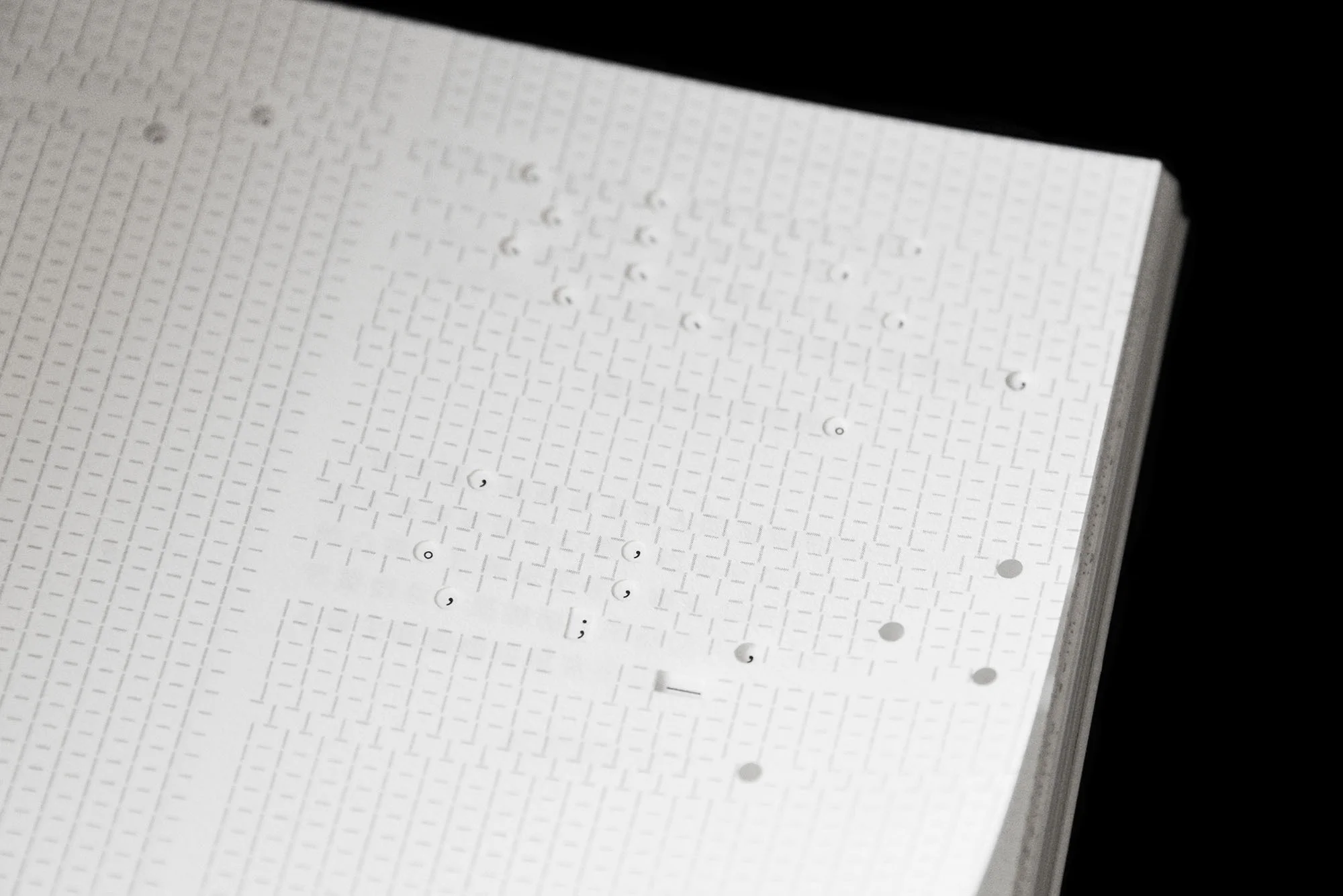 Close-up of a stack of white sheets with a patterned design, offering a textured and geometric aesthetic on a dark background.