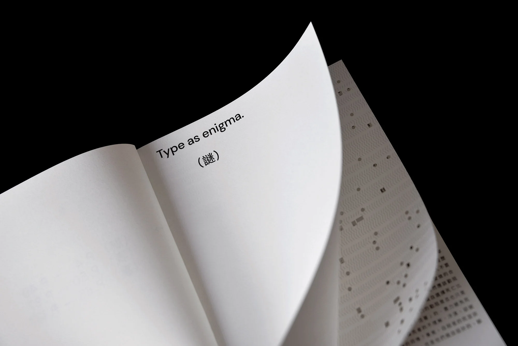 Open book with the text 'Type as enigma' displayed on a white page, set against a black backdrop, showcasing typography.