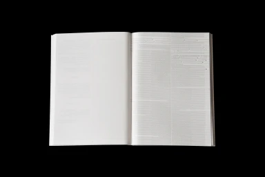 An open white book with printed typography on the right page against a solid black background.