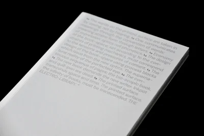Close-up of a white book edge featuring printed typographic text on the translucent cover against a black background